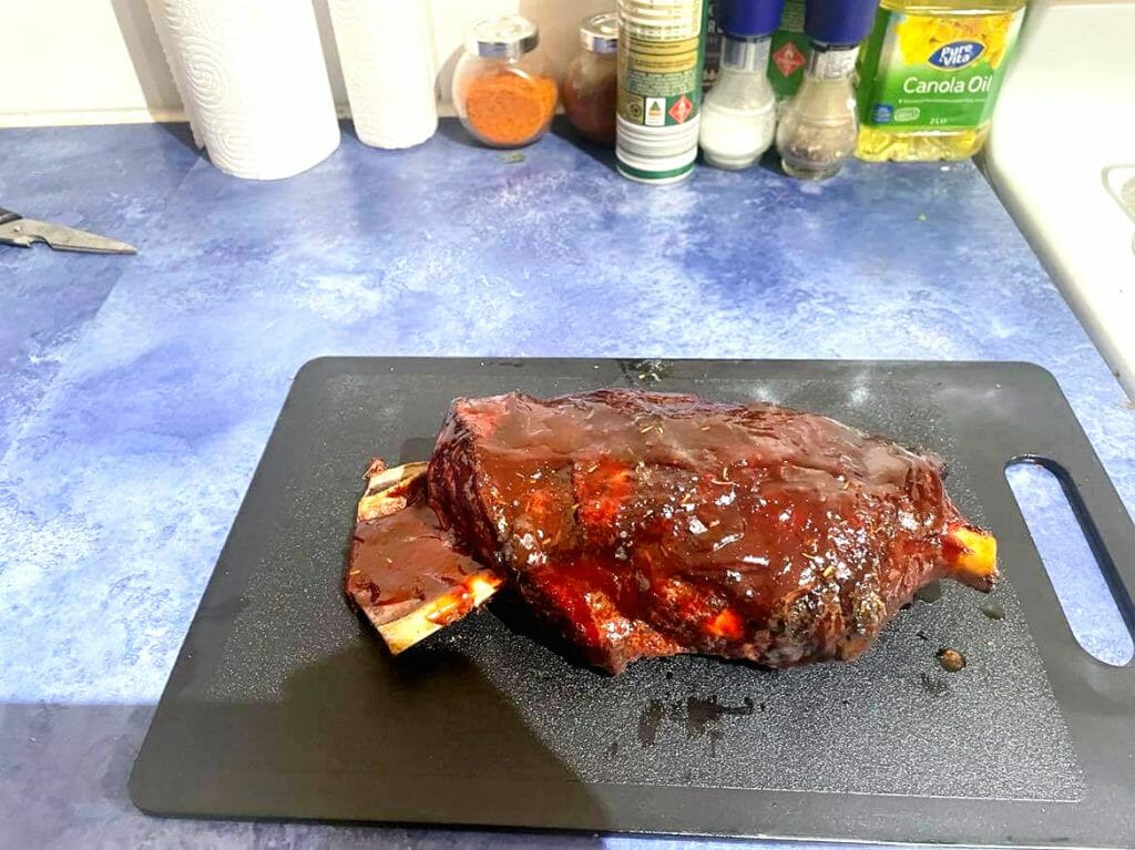 slow cooked bbq lamb shoulder finished cooking and ready to serve with mint sauce